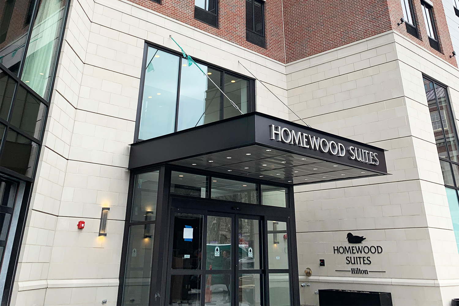 Exterior entrance to building, with black overhead and sign stating "Homewood Suites"