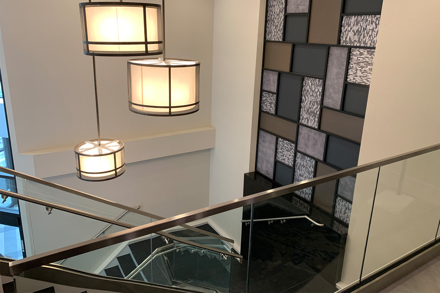 View from top of stairwell: geometric wall design, and elegant lighting fixtures attached to ceiling 
