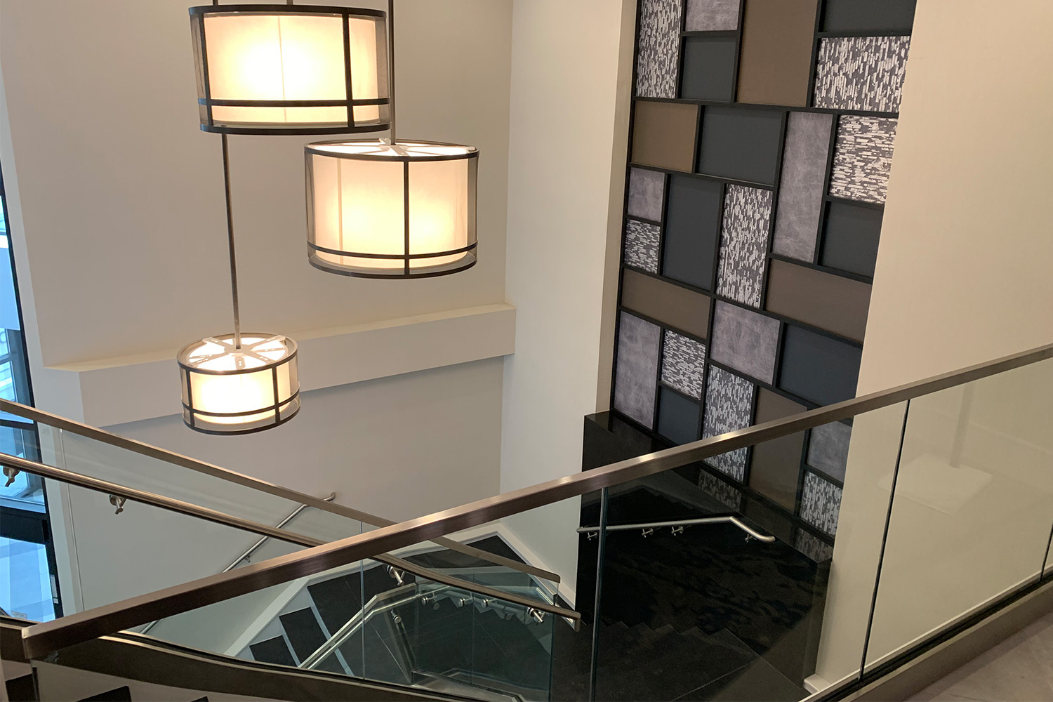 View from top of stairwell: geometric wall design, and elegant lighting fixtures attached to ceiling