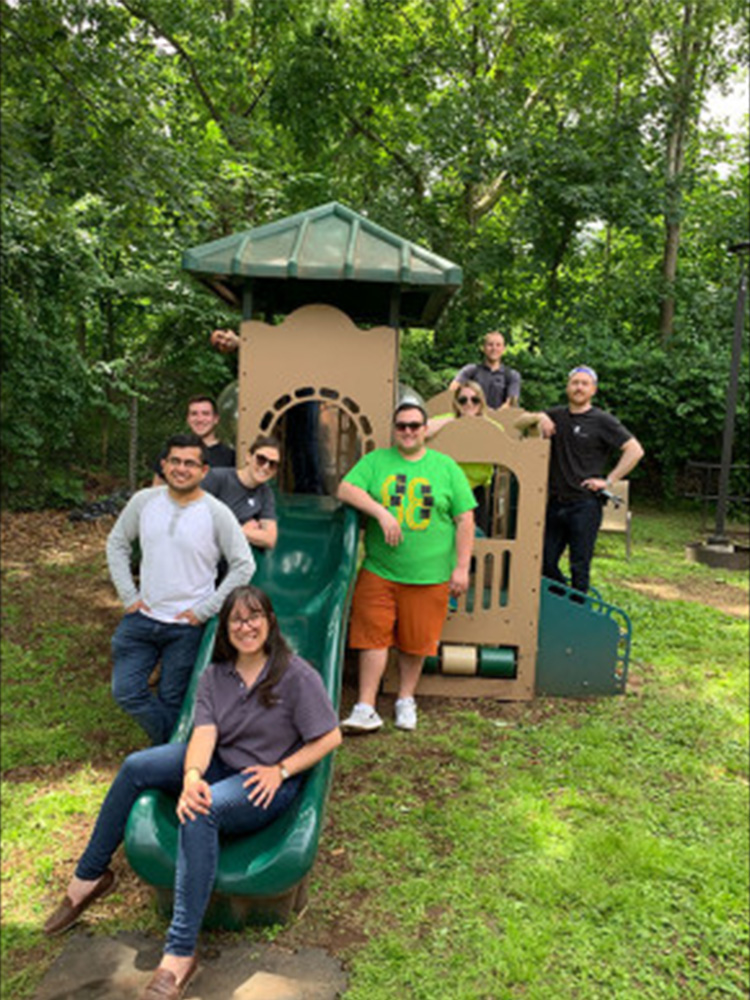 Tocci volunteers posing for group photo by kids playground 