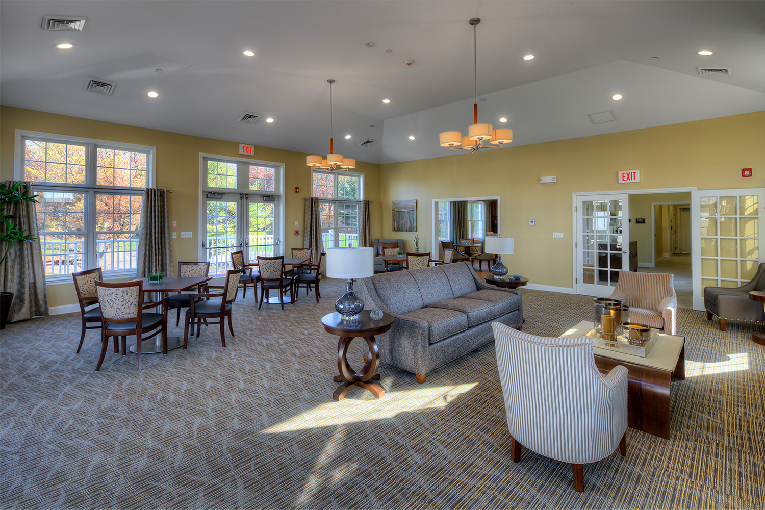 Wide open room with plush seating and tables, glass doors leading to the outside