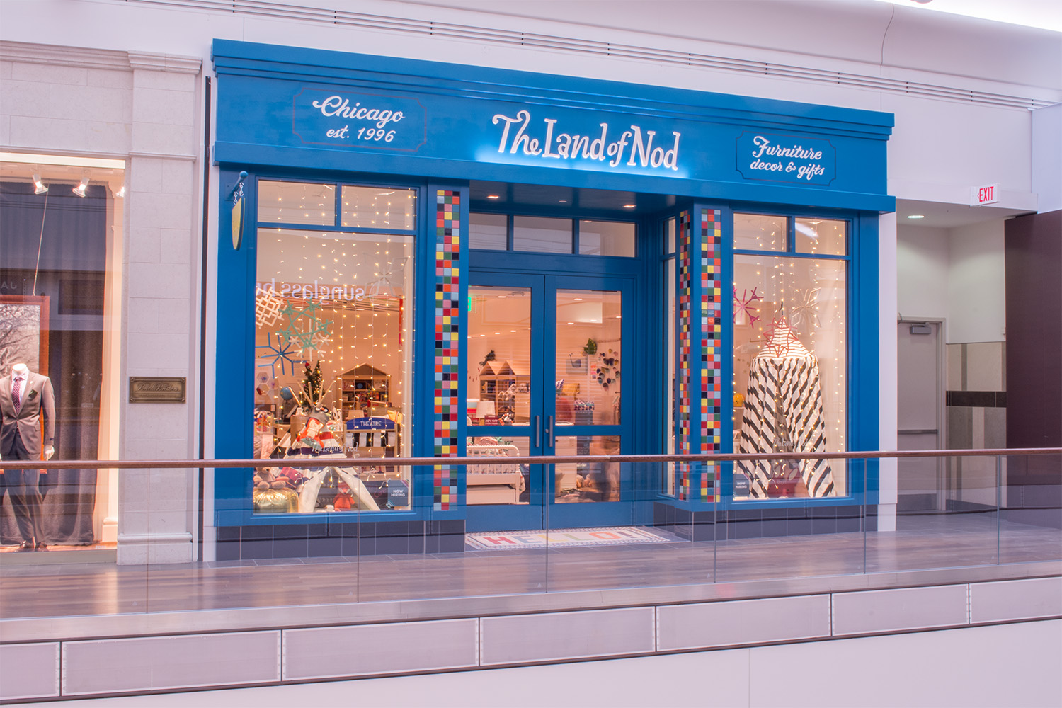 Exterior of store, with blue wood paneling, and cursive-written store sign at top of entrance 