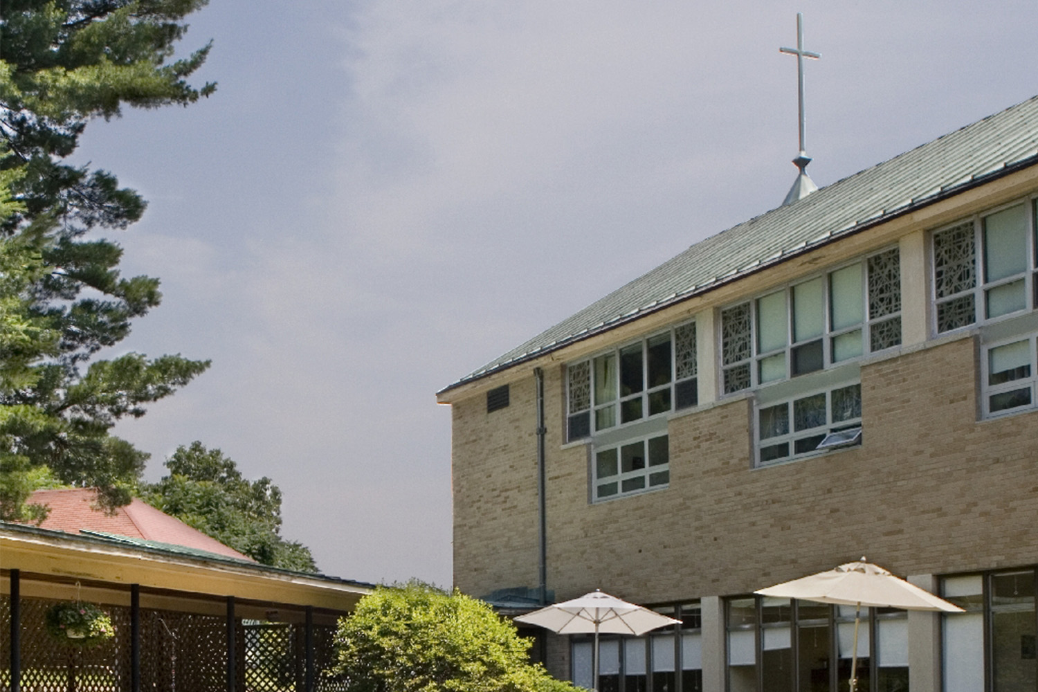 Exterior of mental health wing, with green tile roof and holy cross mounted on top 