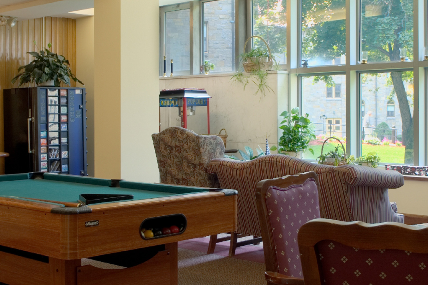 Classic pool table with vending machine, and large window allowing ample lighting 