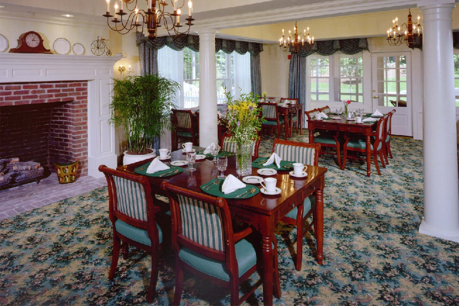 Dining area with fireplace, multiple large windows, and cherrywood chairs and tables 