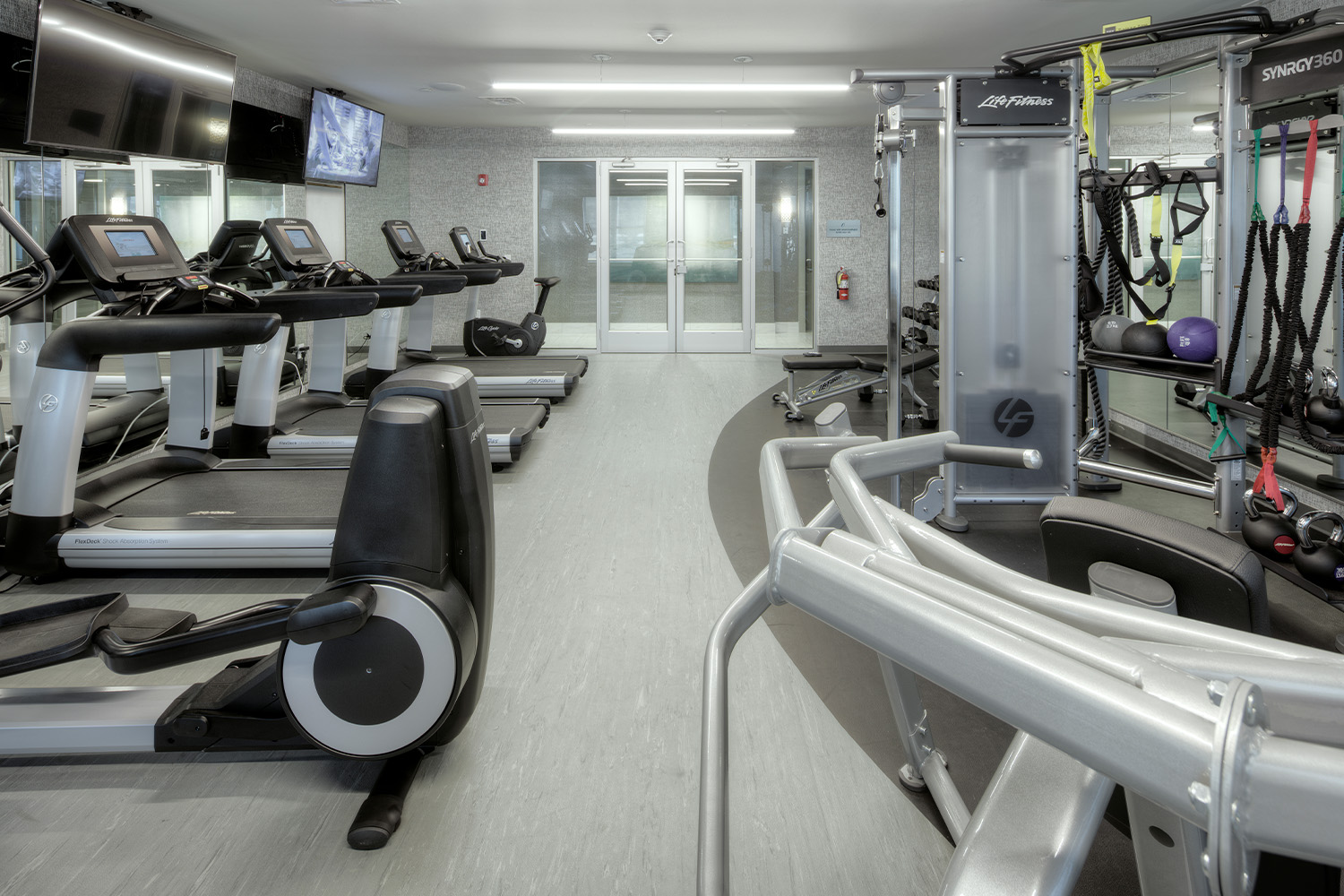 Clean gym with minimalist style light fixtures, and exercise equipment