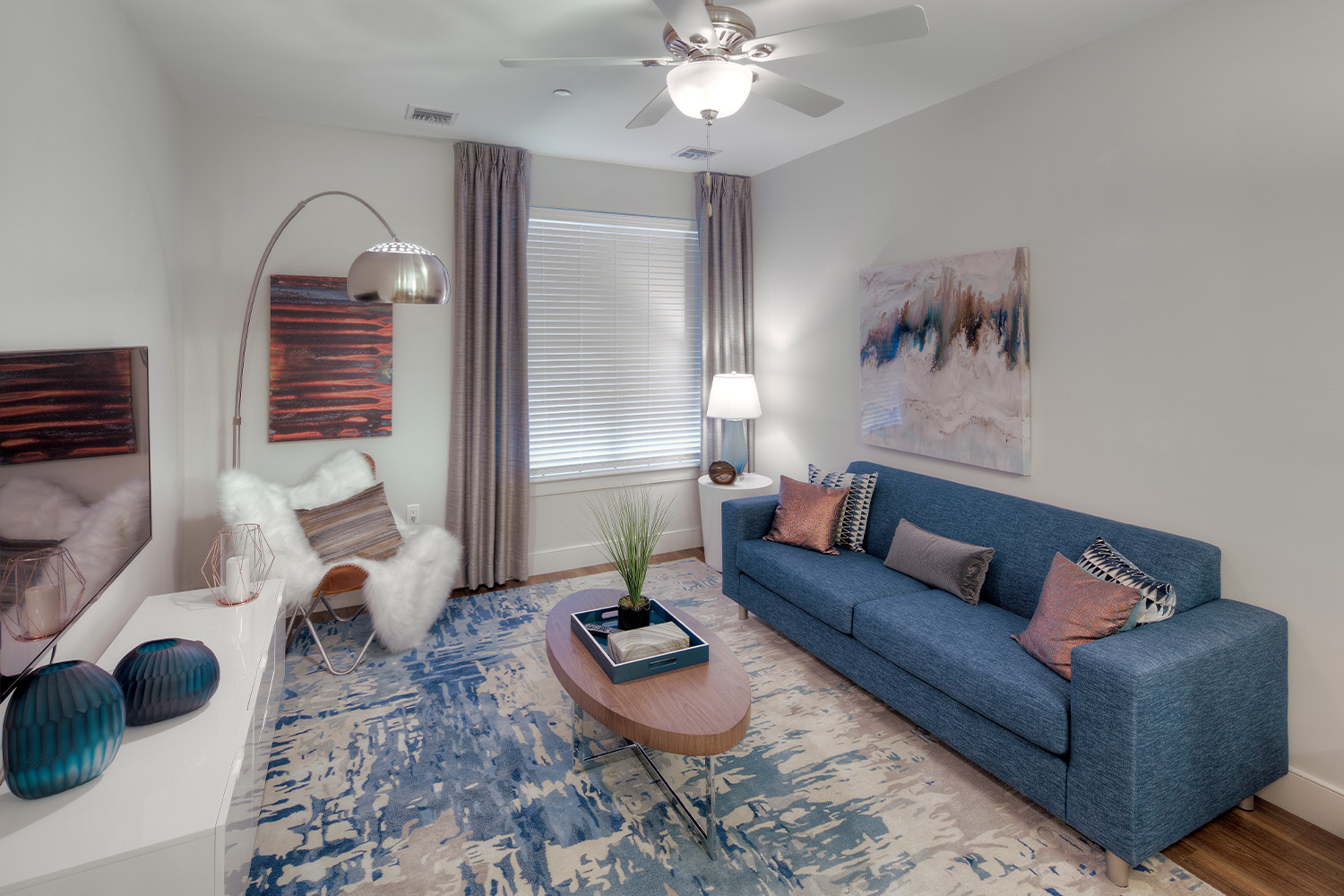 living room with retro blue couch in front of wooden table and behind TV mounted on wall 