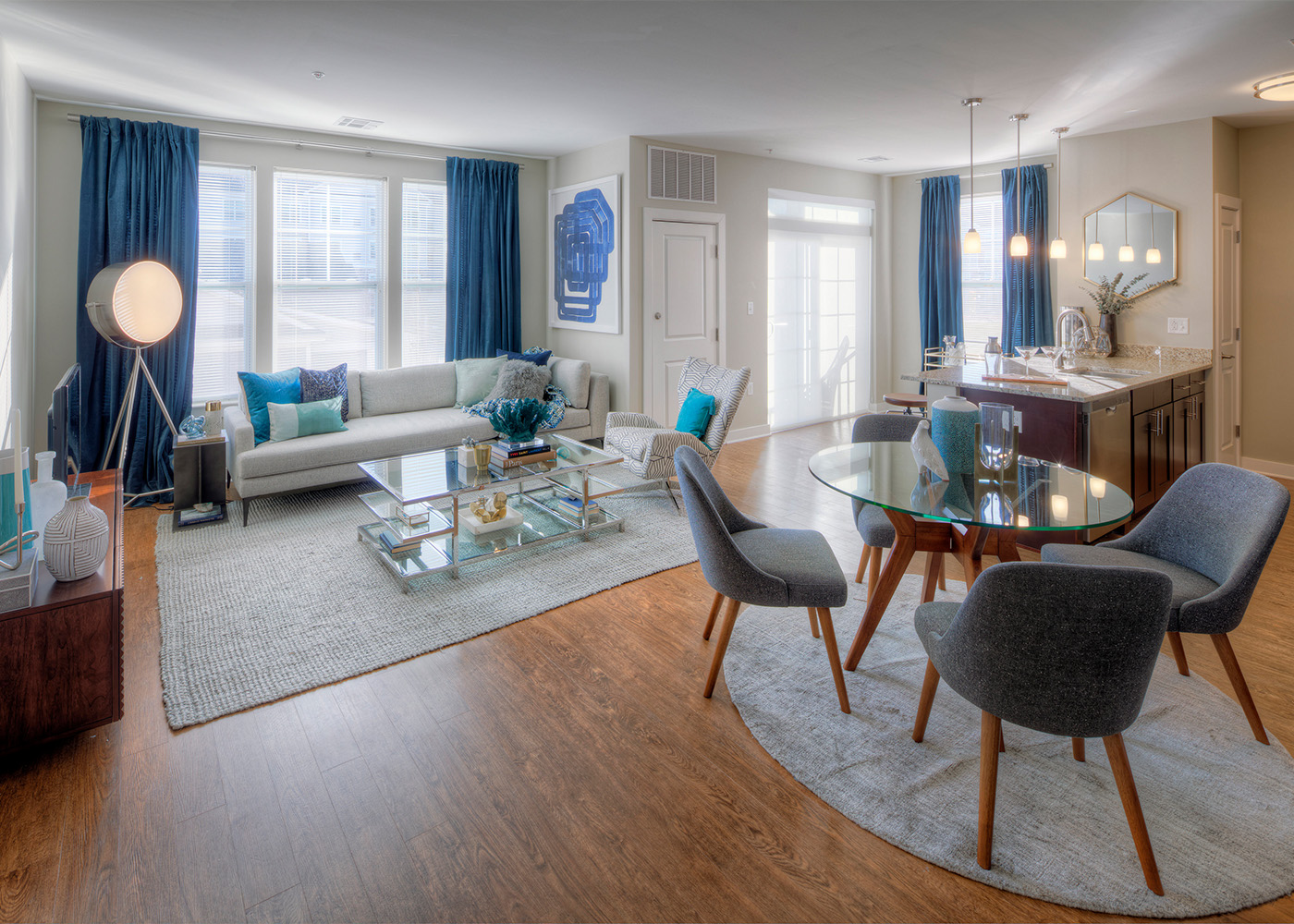 Living area with retro grey plush chairs, big bright windows, and couches