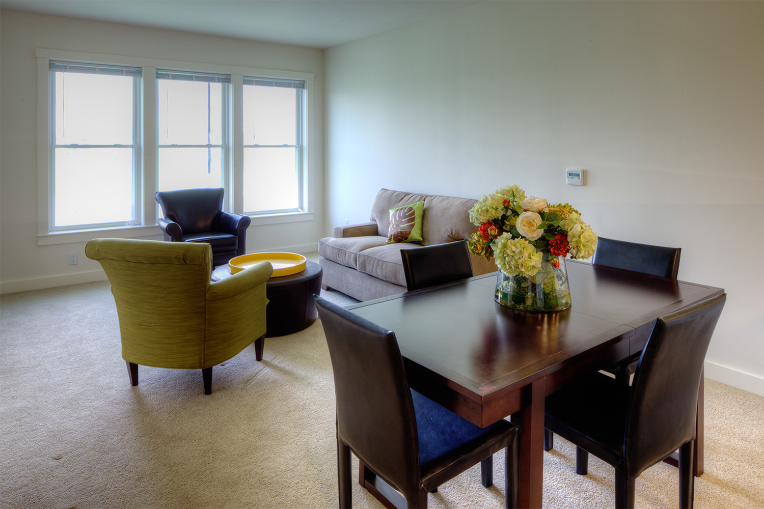 Living room with couch and 2 chairs, and dining room with black table and chairs