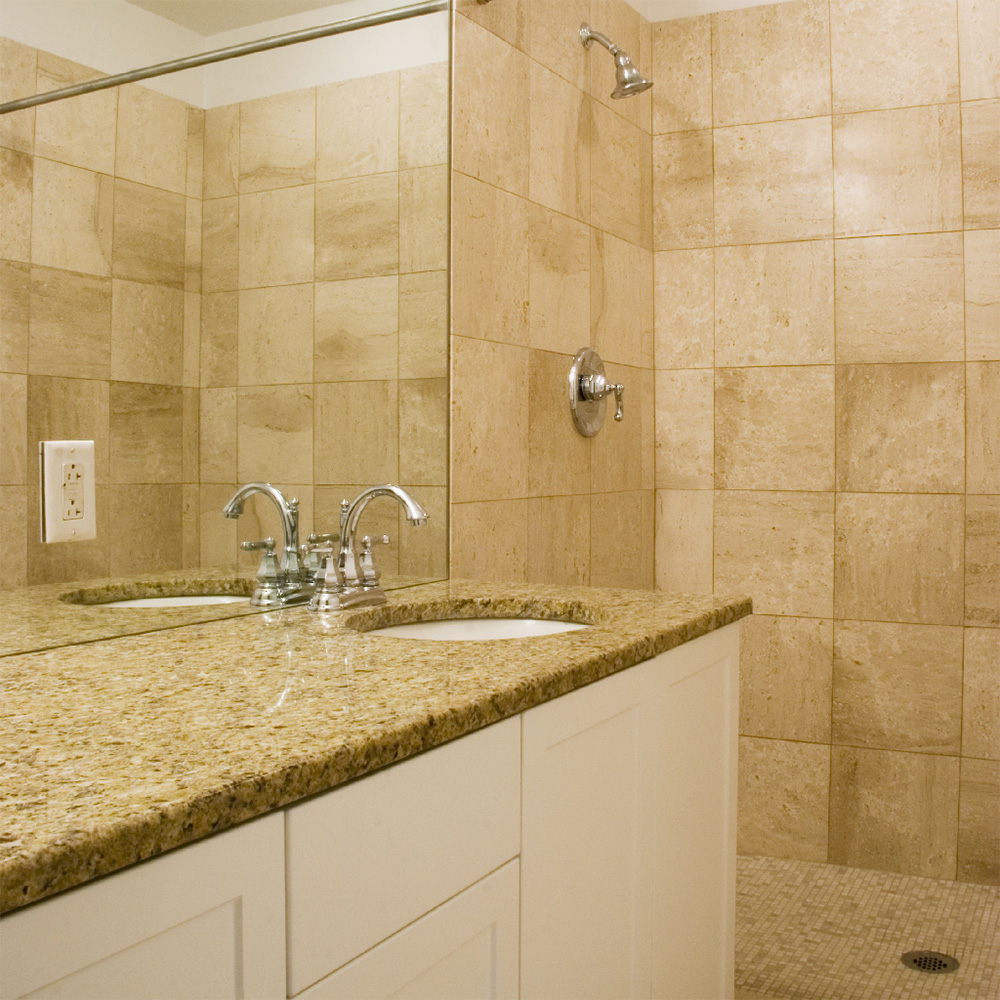 Bathroom with brown granite countertops, and brown tiled stand-in shower 