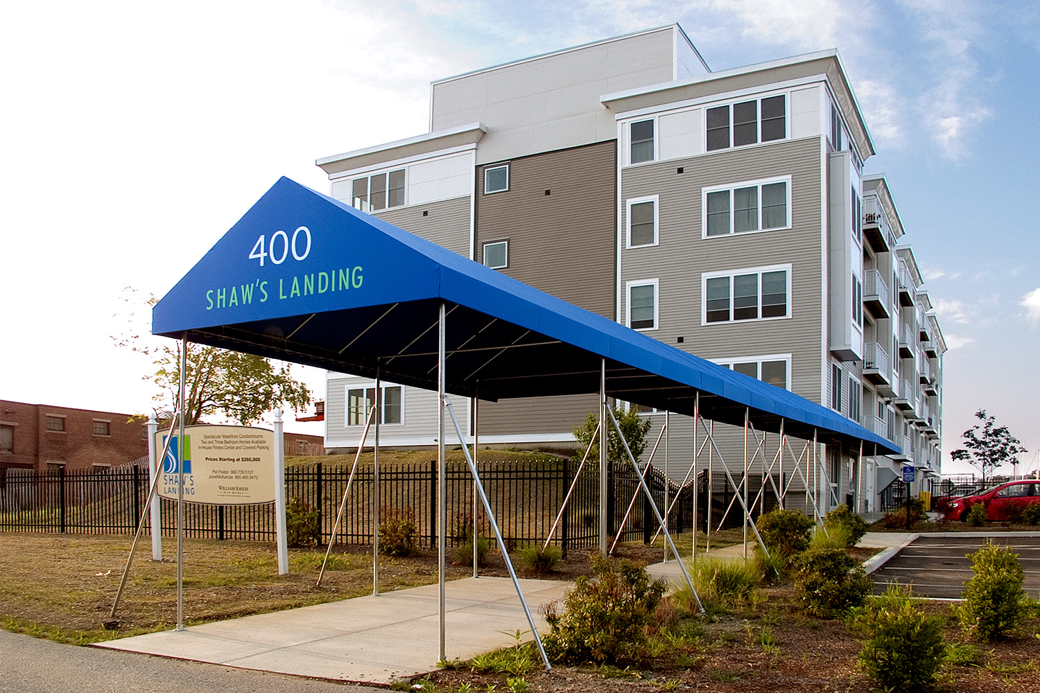 Sideview of building, with long blue tent propped over walkway to entrance 