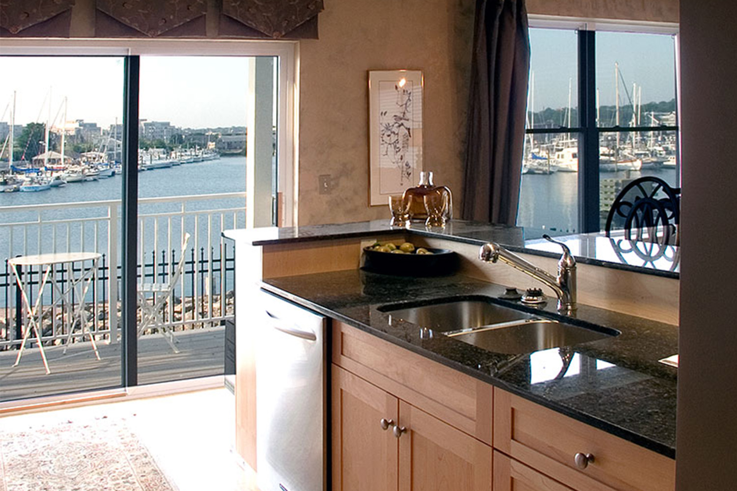 Kitchen with black granite countertops, sink, and large sliding glass doors to balcony area 