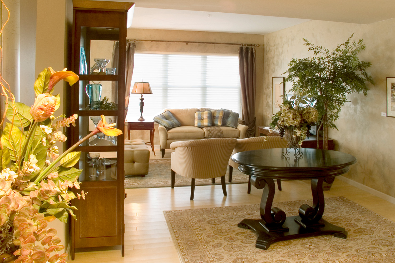 Living room with plush tan couches, chairs, and rug, and small brown/black table 