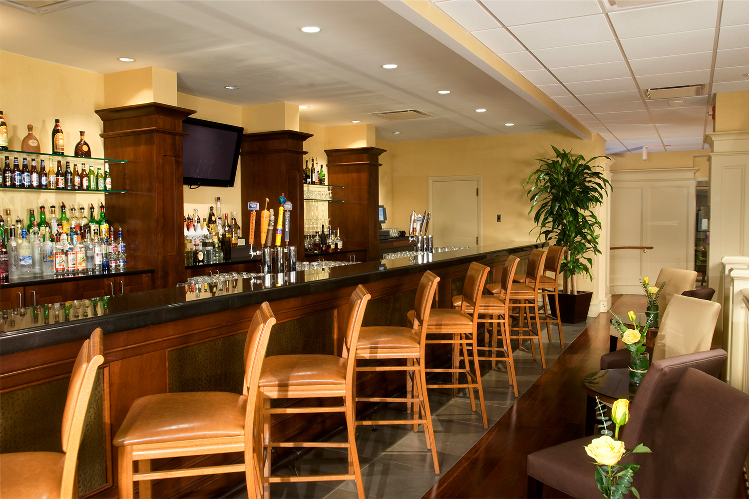 Long mahogany wood bar table and chairs, in front of plush seating