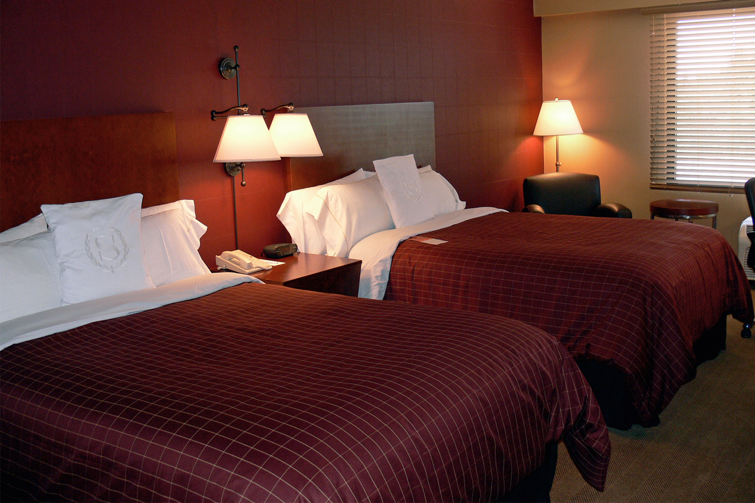 Bedroom with maroon duvet bed covers, medium-sized window, and wall covered in red tile design