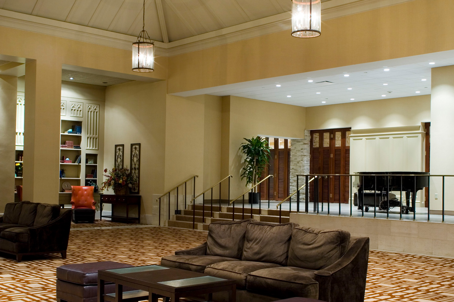 Lounge area with tall ceiling, light fixtures, and plush brown couches 