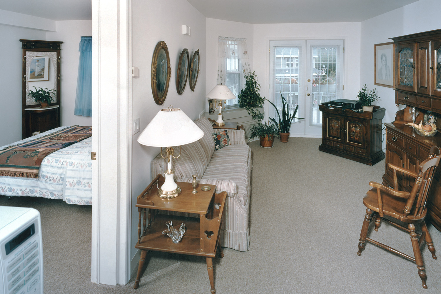 Quaint living area complete with couch, bookcase, bedroom, and 3 windows