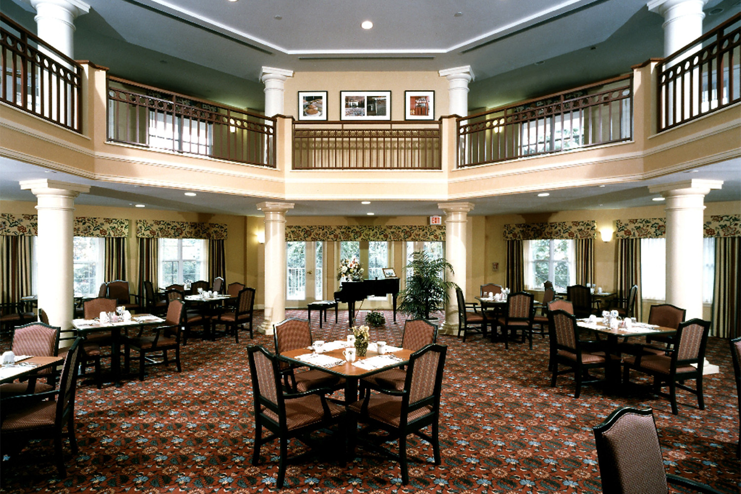 Octagonal dining room, with wooden chairs and tables, and windows on every wall 