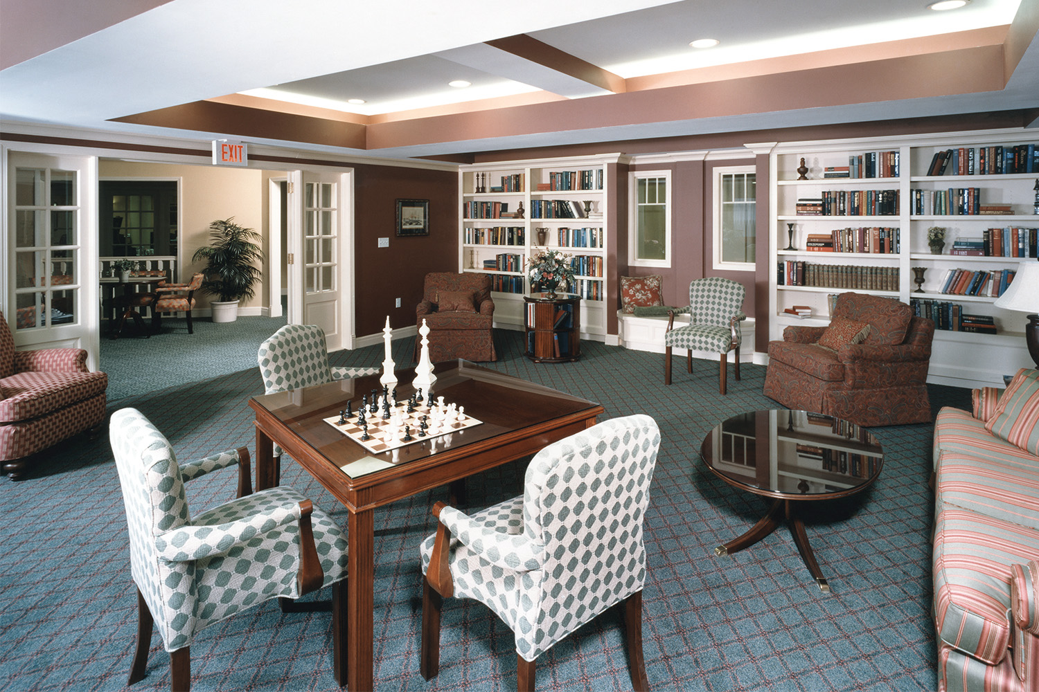 Organized library area with white bookcases, chess set, and seating