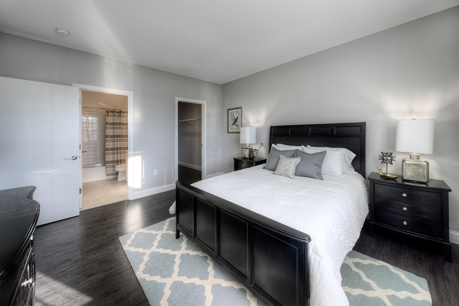 Bedroom with bed in blackwood bedframe, soft rug, and 2 interior doors