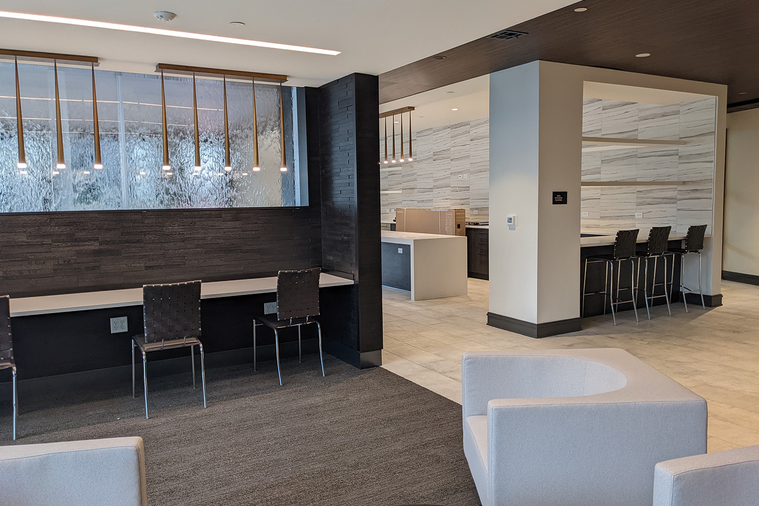 Flats on First's indoor amenities on ground floor. There is a water feature near a bar area, full kitchen, and ample seating. The exercise room is off to the left.