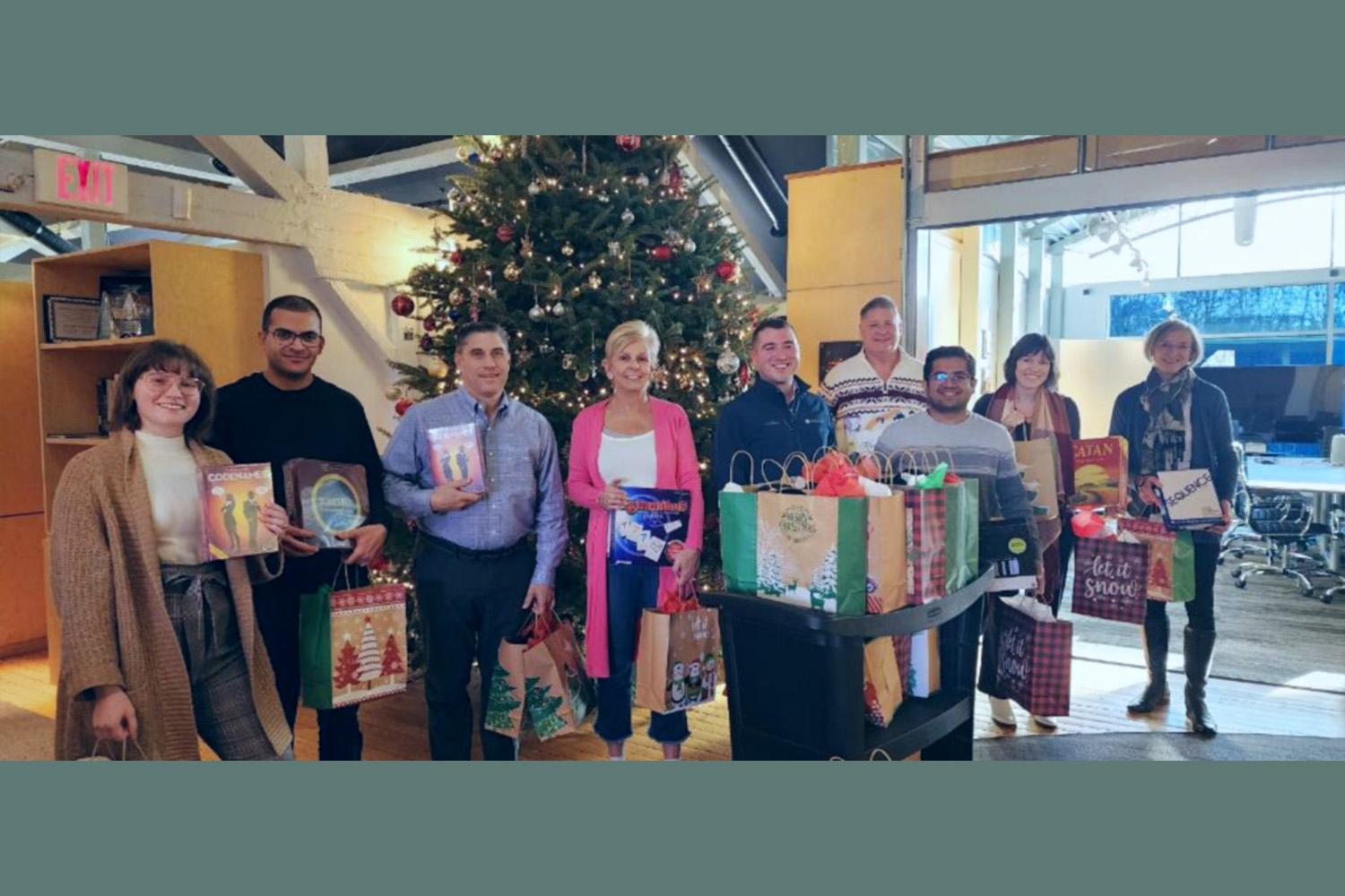 Group stands in front of Christmas tree, donating gifts to non-profit