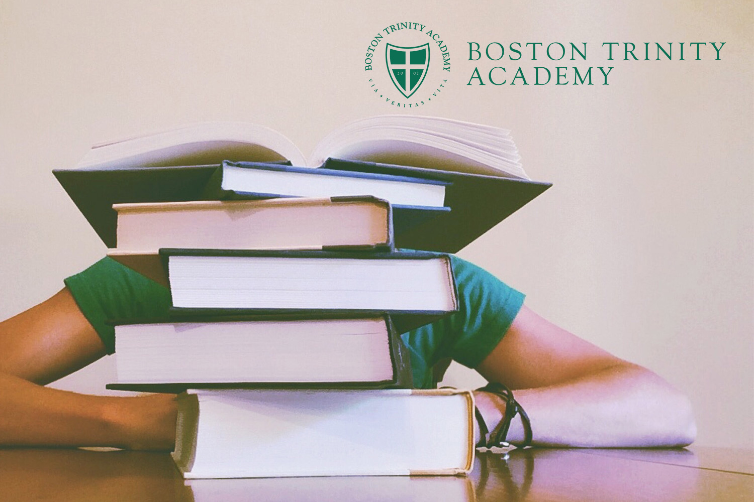 A stack of book with Boston Trinity Academy logo 