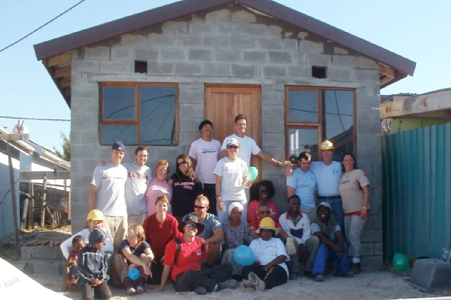 Habitat for Humanity volunteers pose in front of newly constructed house 
