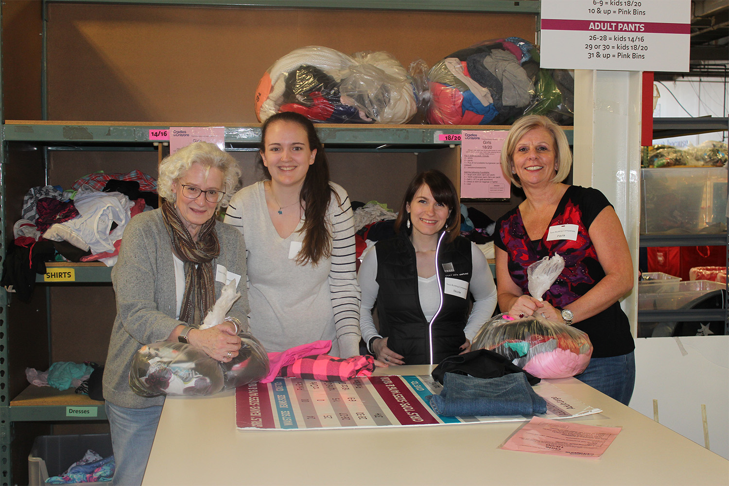 Tocci volunteers standing behind table, sorting through clothes 