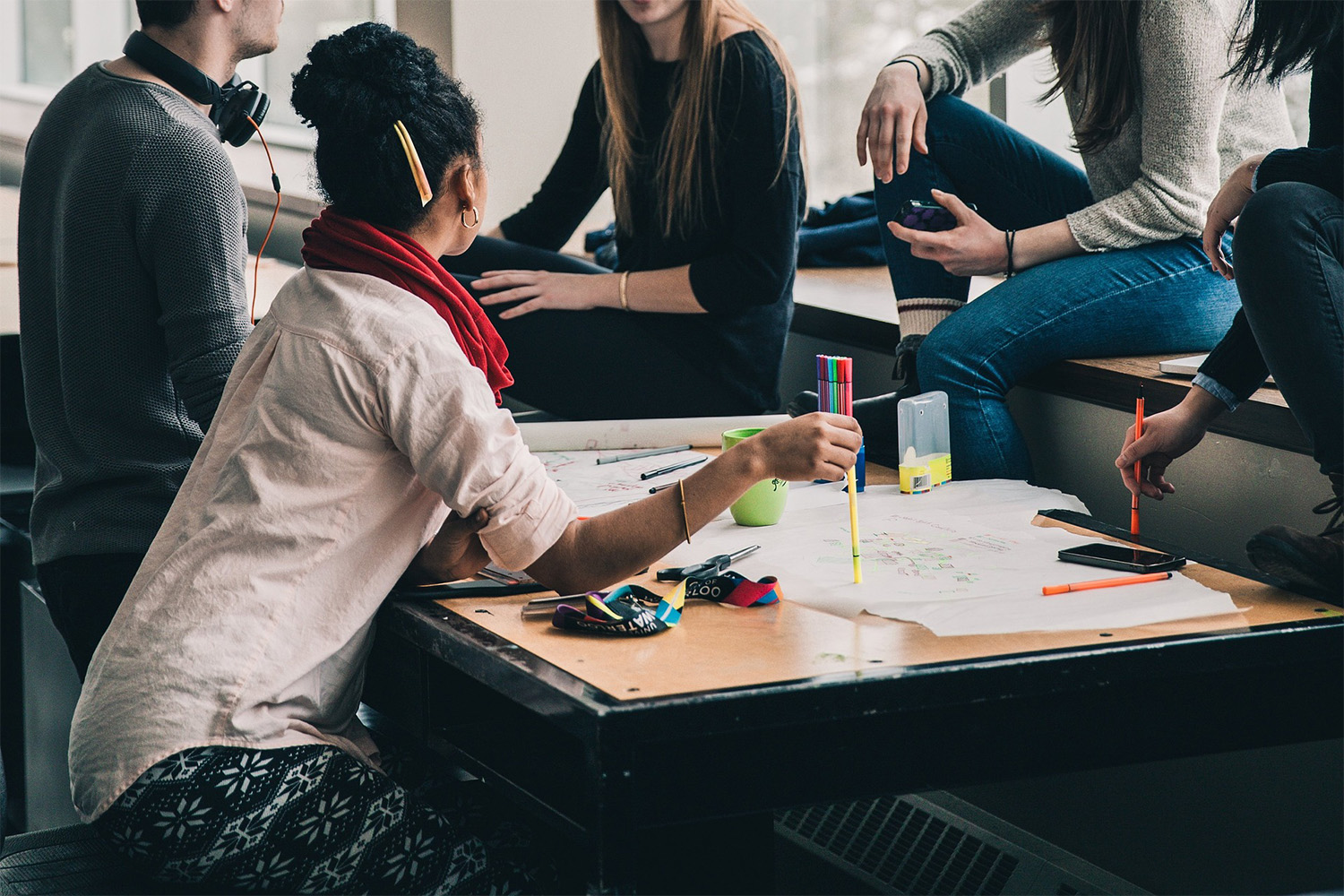 students sitting by a table, collaborating on a project 