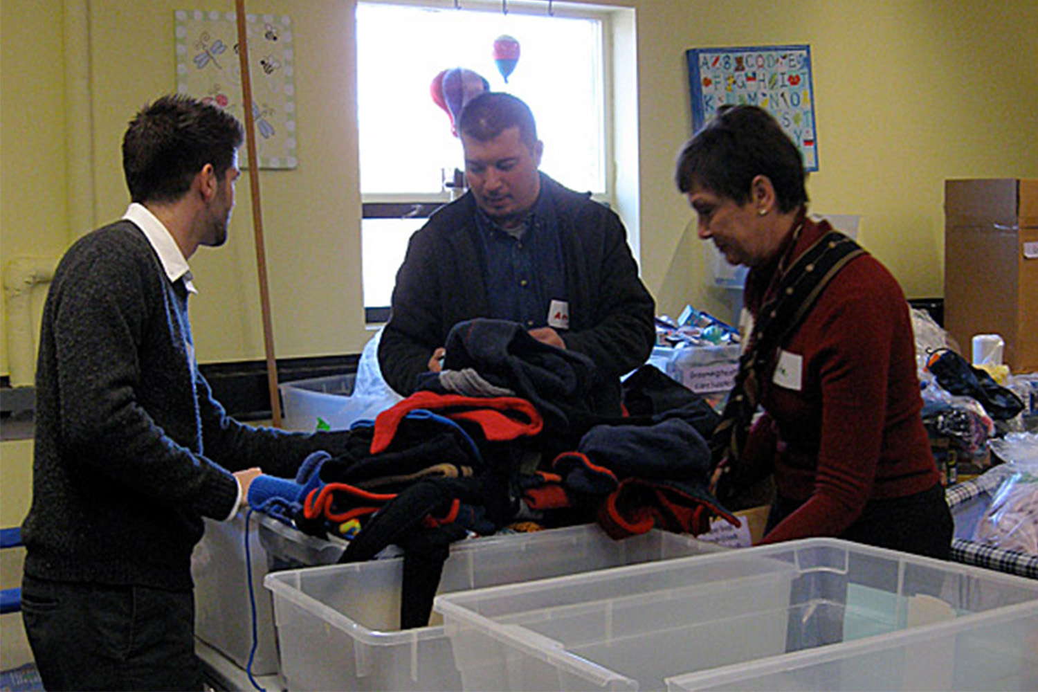 3 Tocci volunteers sort through bins of donated clothes 