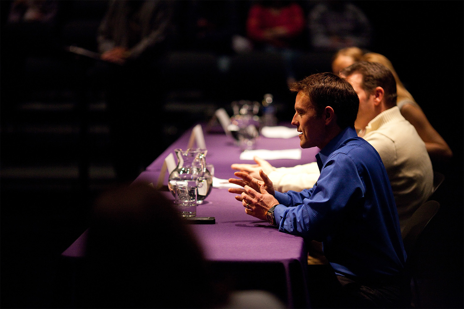 people sitting behind purple table for panel discussion 