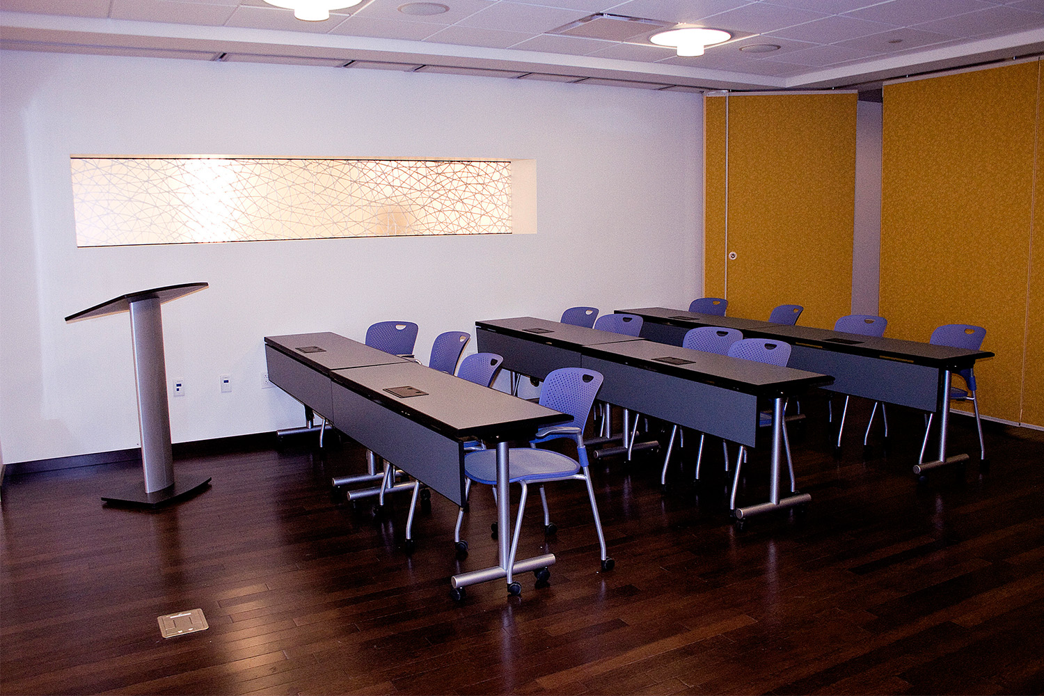 training room with long wooden tables and blue chairs 