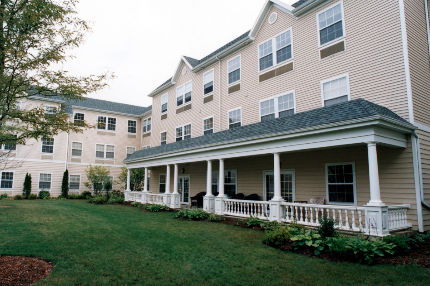 tan building with porch, seen from across grass lawn