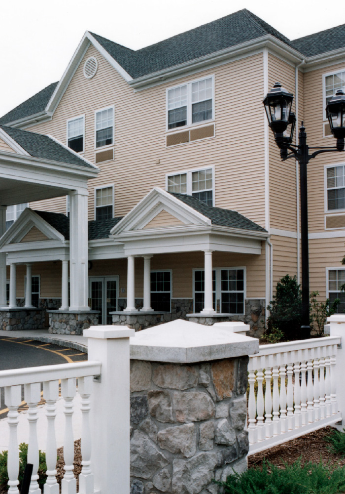 Entrance of tan building, with white picket fence around 