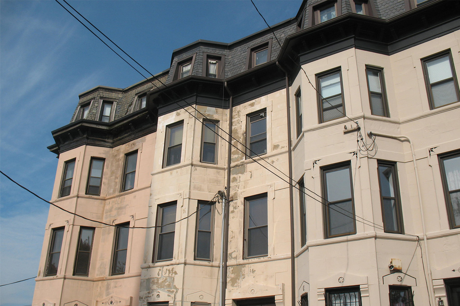 worm's eye view of a tan apartment complex in the Forthill neighborhood in Roxbury