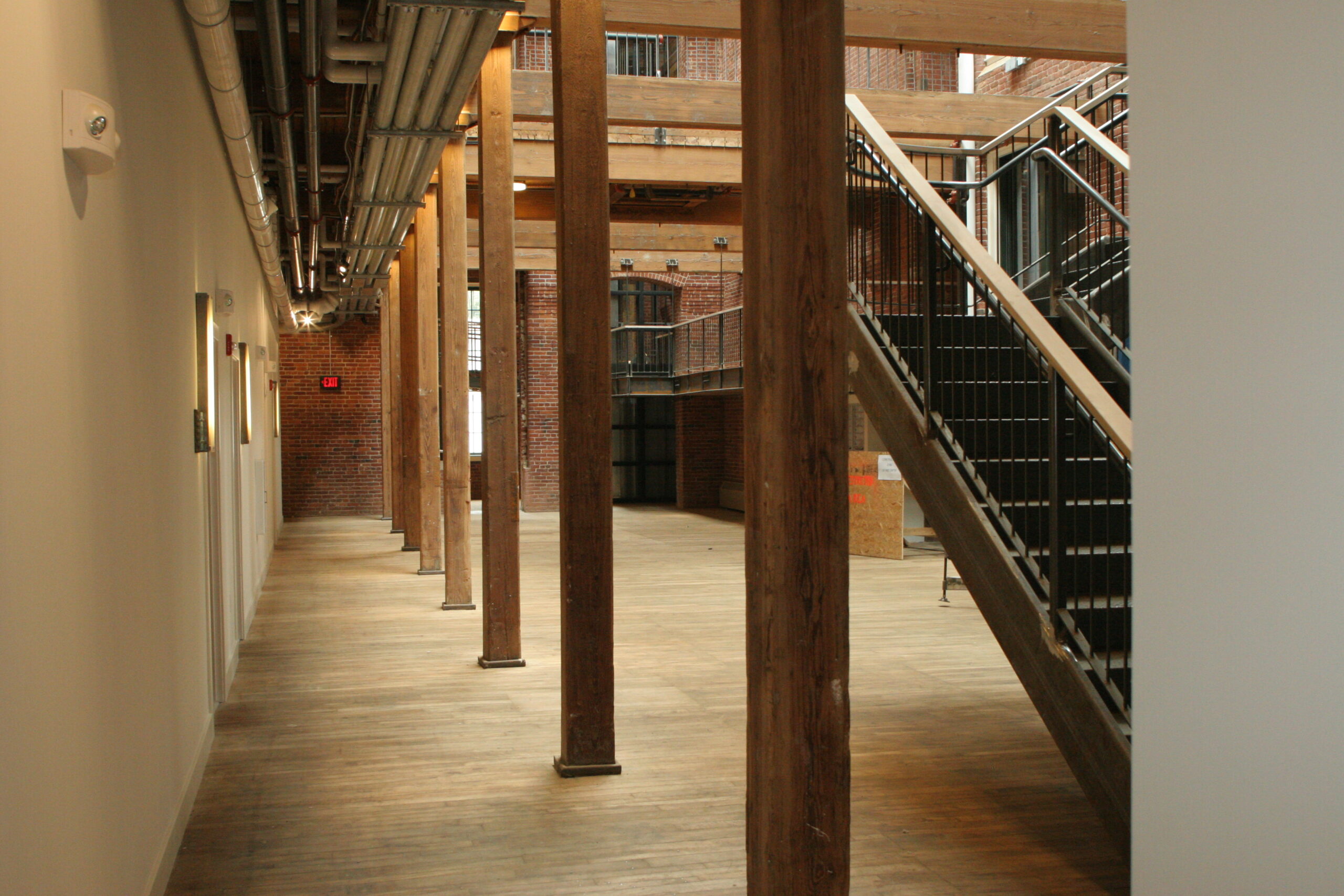 spacious room with wooden ceiling and floors, next to black metal staircase 