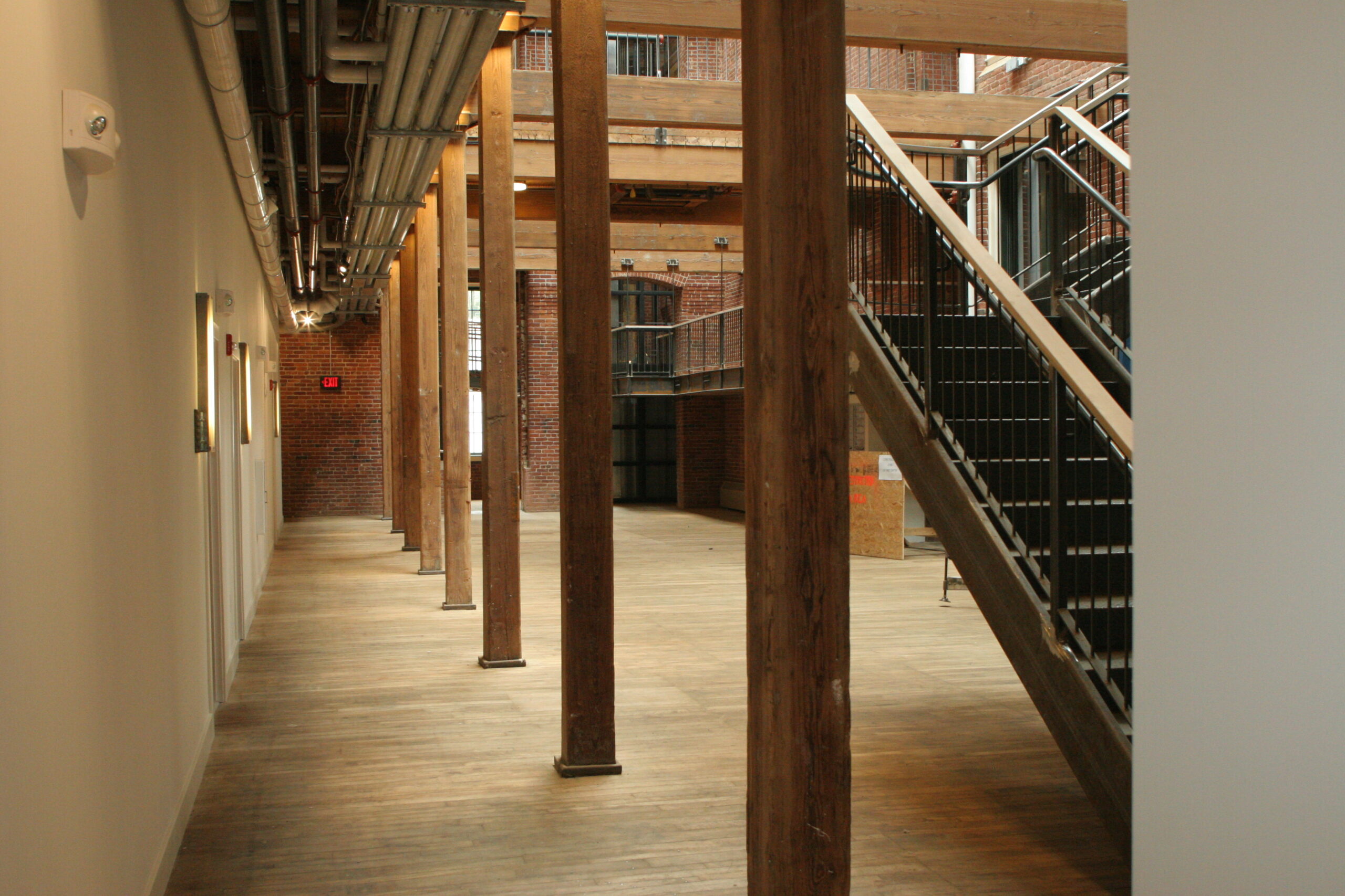 spacious room with wooden ceiling and floors, next to black metal staircase