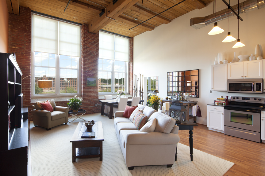 A living room with white couch, view of kitchen in the background