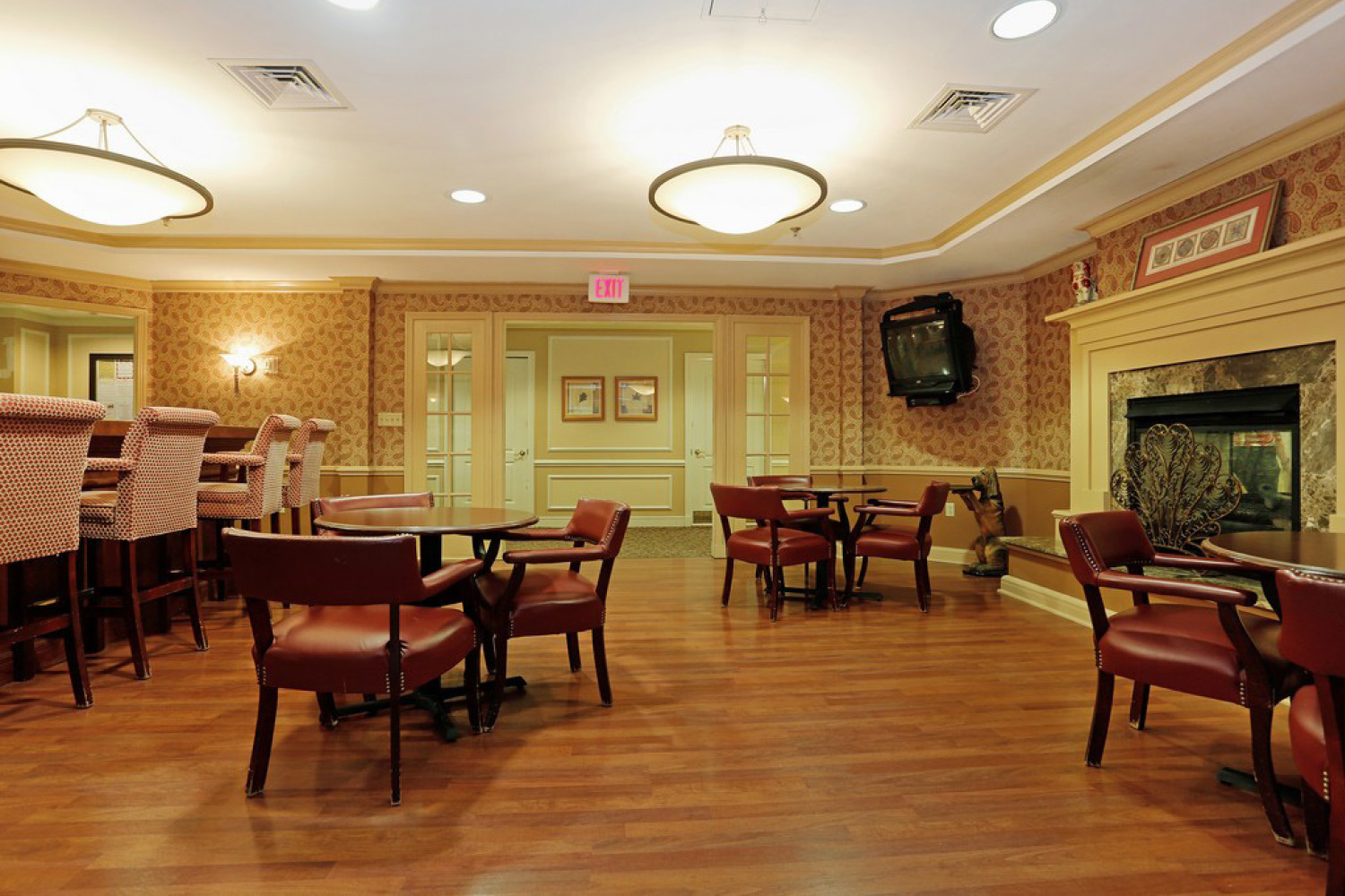 Dining area with dark wooden tables and chairs, a fireplace, and a bar area 