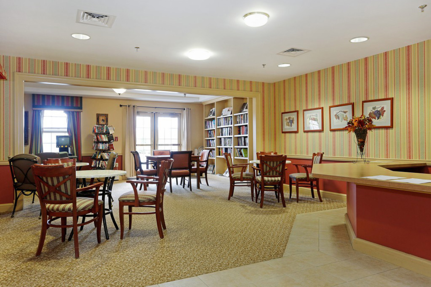 recreation room with a bookshelf, chairs and tables, and large windows