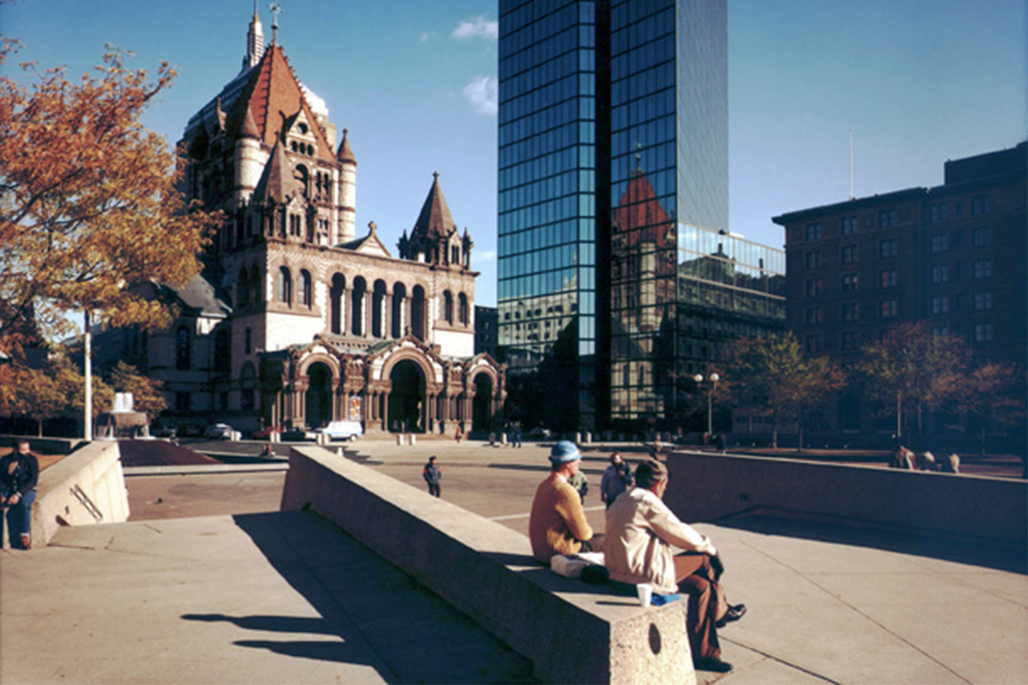 View of the Trinity Church in Boston, with two elderly people sitting on a bench