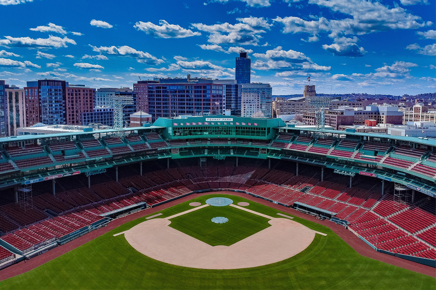 An aerial view of Fenway Park, with view of skyscrapers behind it