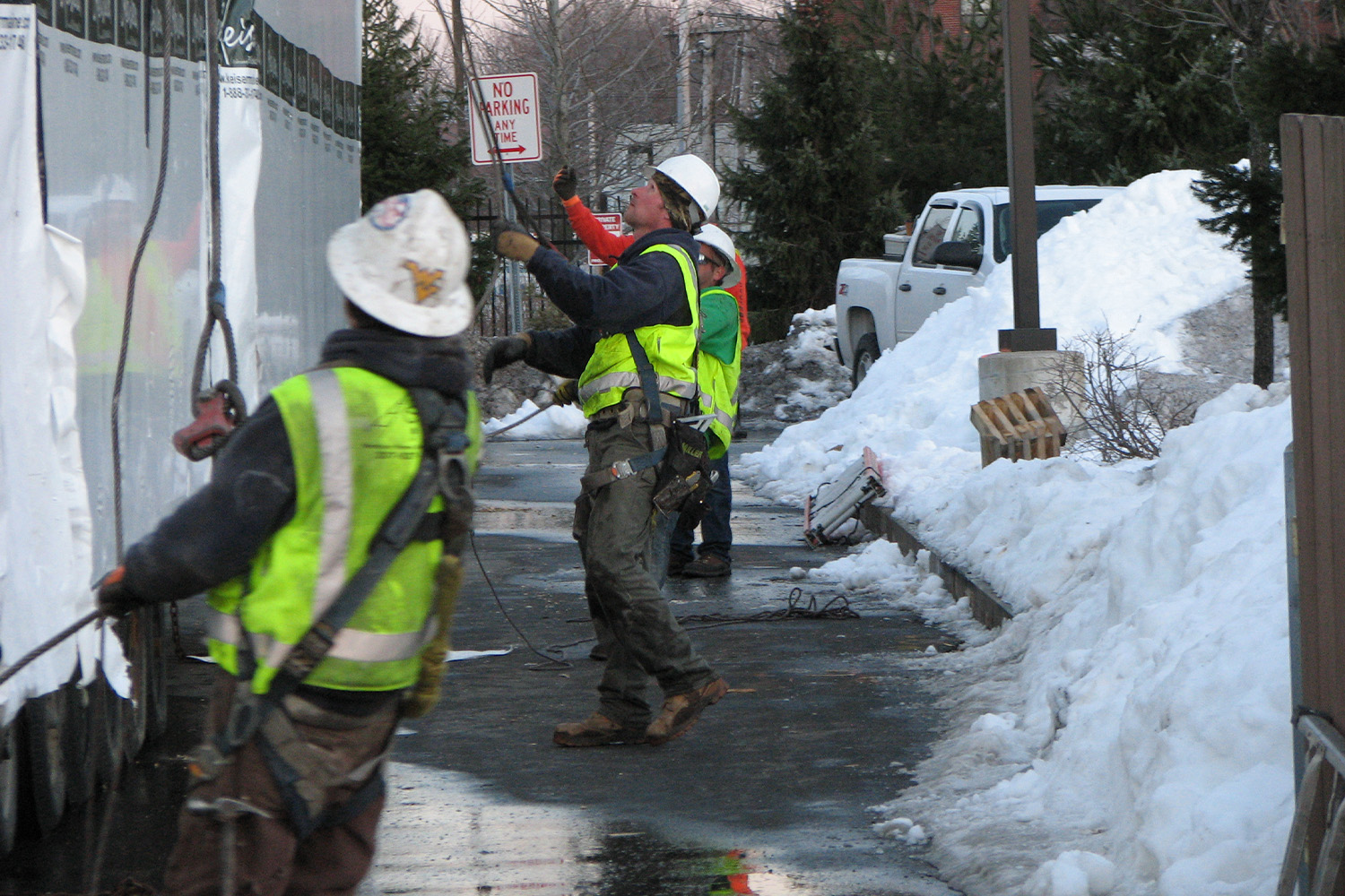 3 construction workers facing the left directing, working on a wall