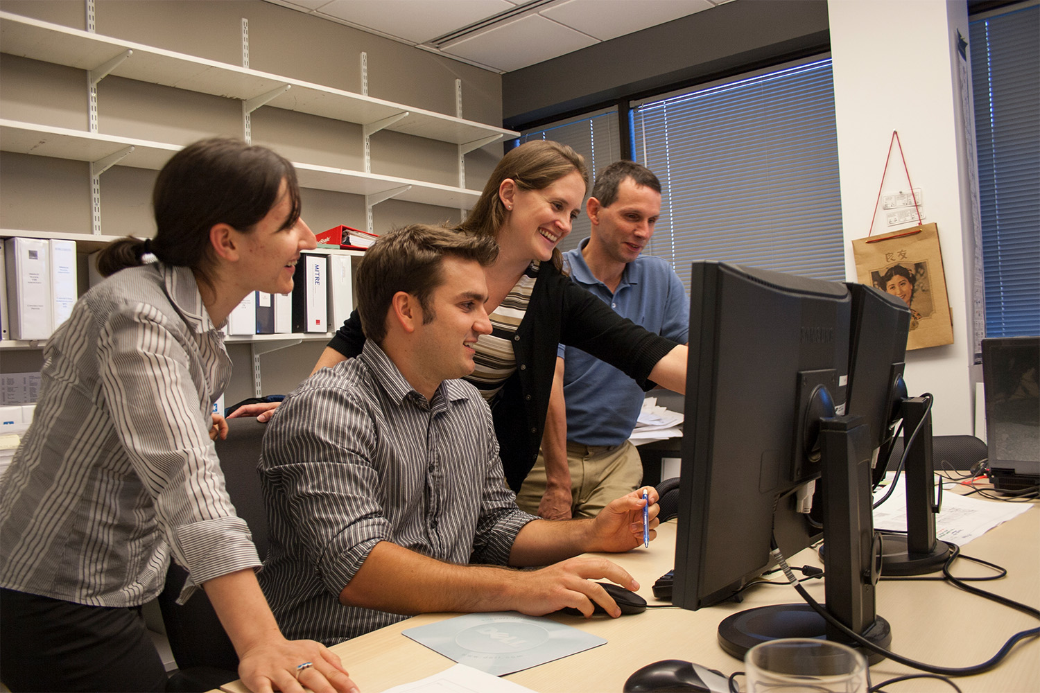 4 Tocci employees looking at 2 monitors, smiling and pointing 