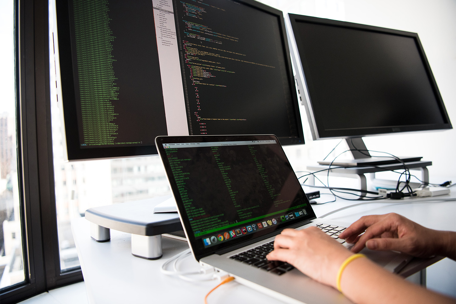 woman using software on laptop and 3 monitors 