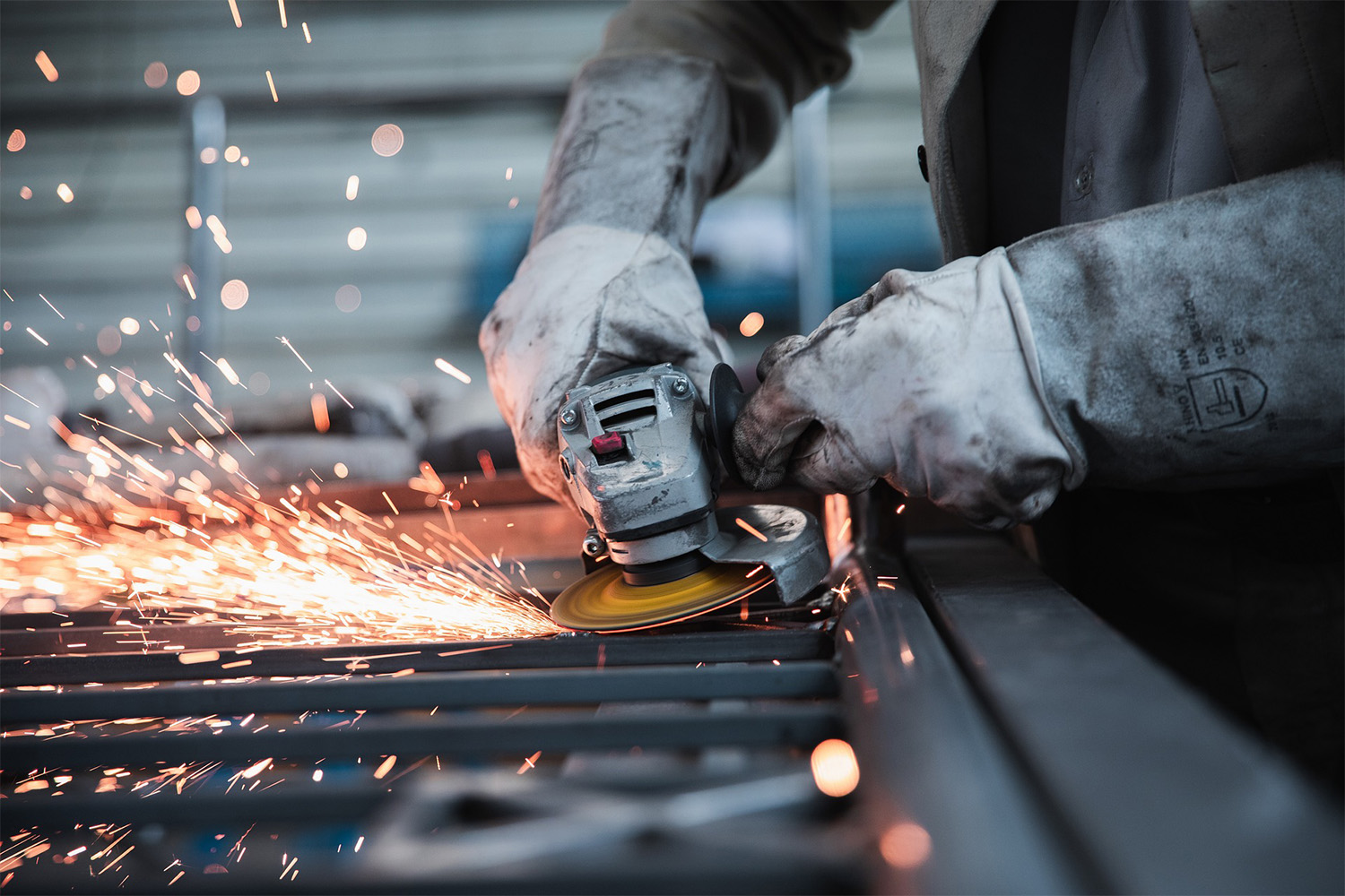 two hands with protective mits on, sawing steel sheets 