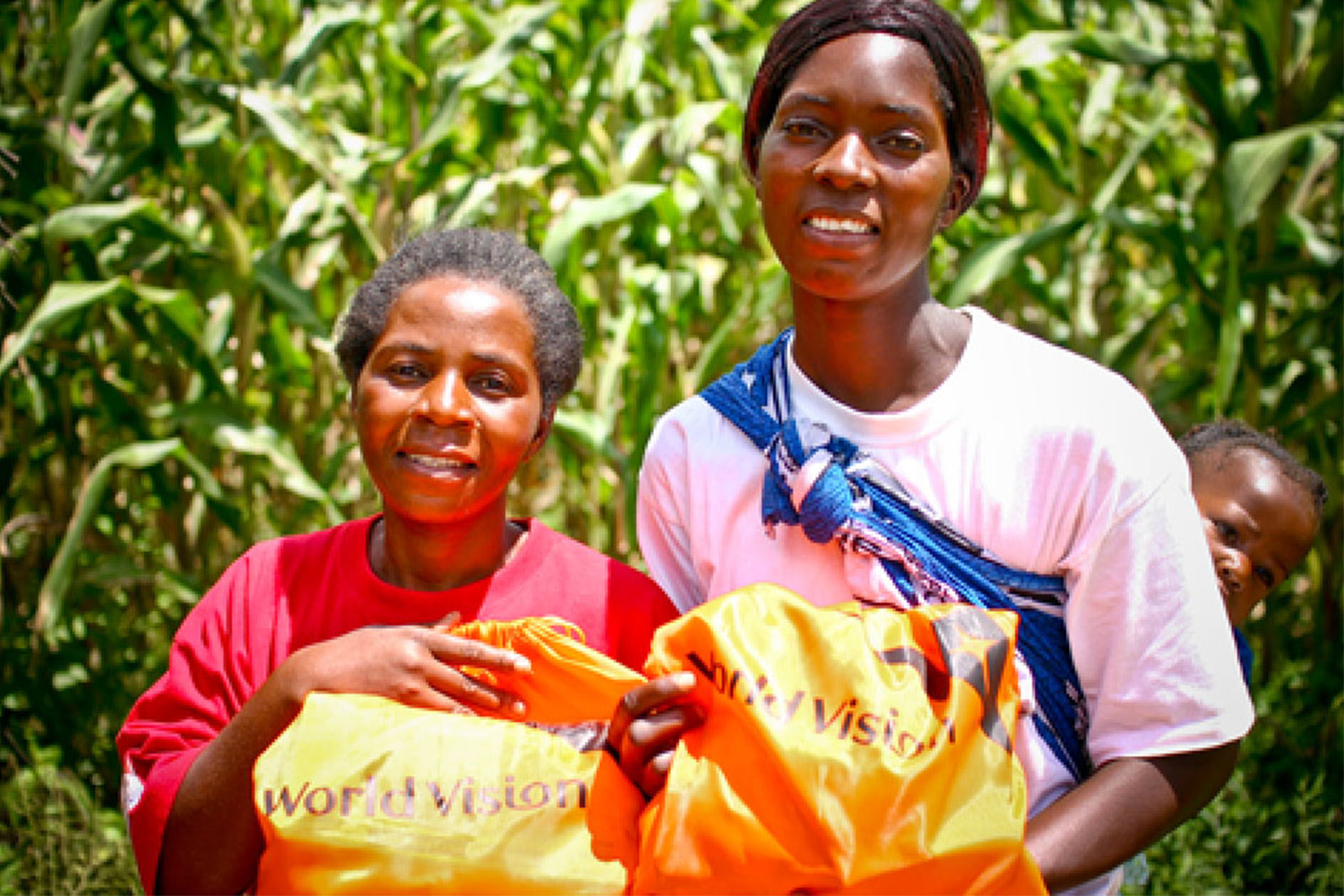 2 women holding orange donation bags 