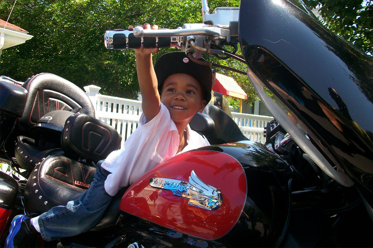 a little boy posing for photo on a red motorcycle