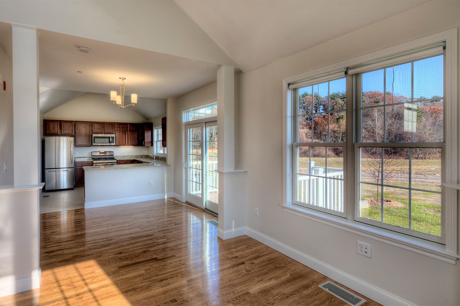 View of spacious living room with wooden floors and big windows 